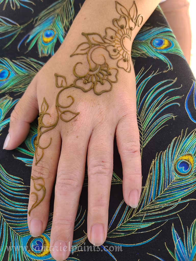 A hand with an intricate floral henna tattoo pattern